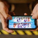 Close-up of hands playing the mobile FPS game Standoff 2 on a smartphone, showcasing the touch-screen game interface