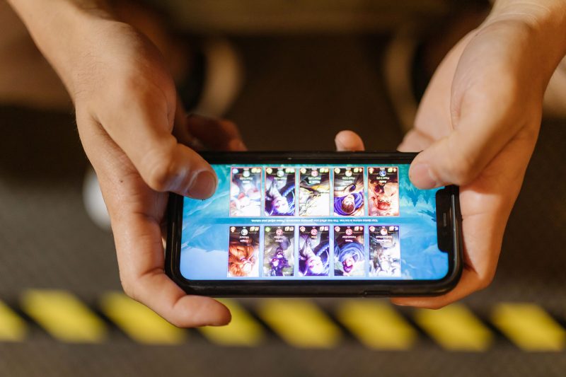Close-up of hands playing the mobile FPS game Standoff 2 on a smartphone, showcasing the touch-screen game interface